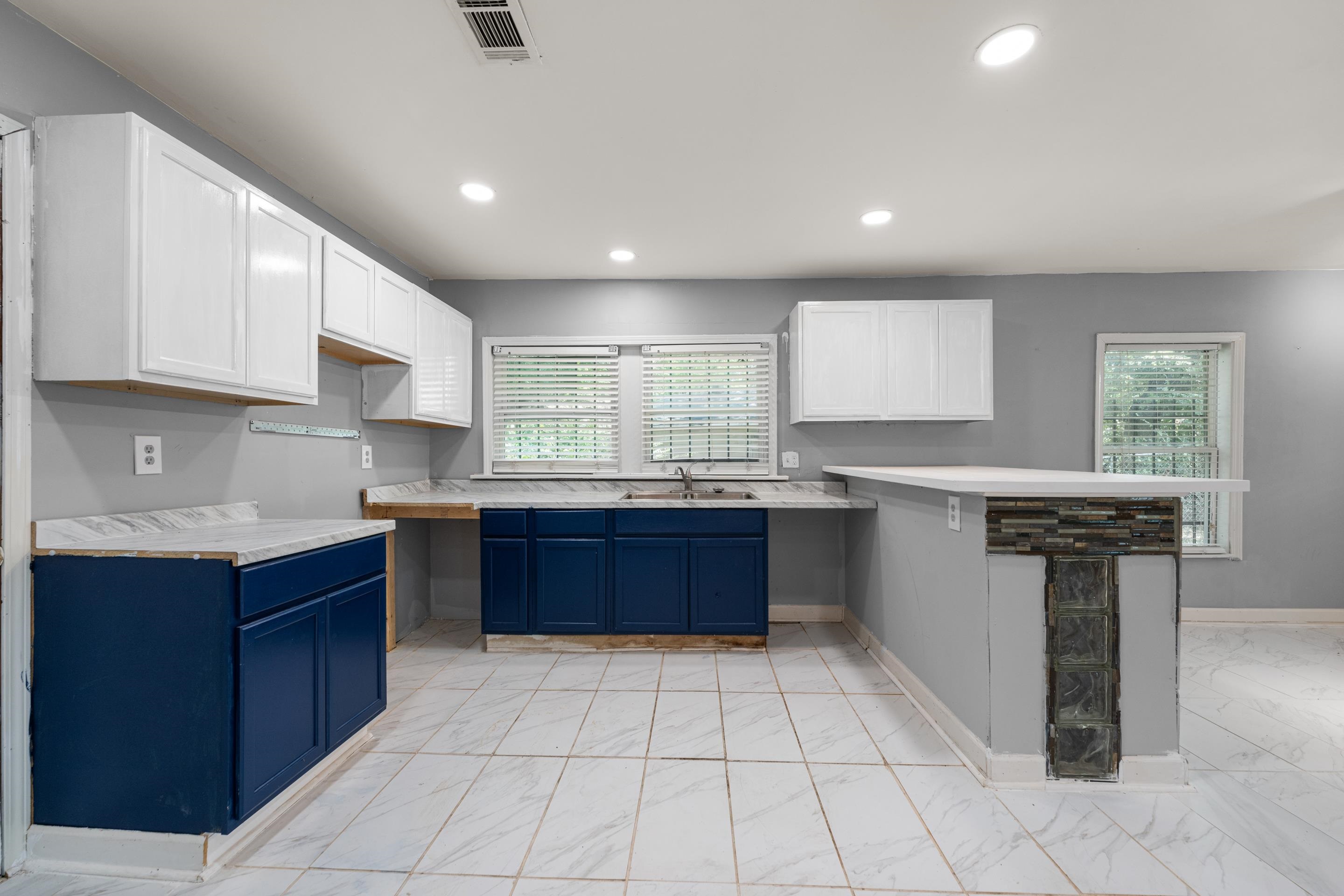726 Harahan Road Memphis, TN 38109 - Photo 13 of 24 Kitchen featuring blue cabinets, light marble finish flooring, a peninsula, recessed lighting, and white cabinetry