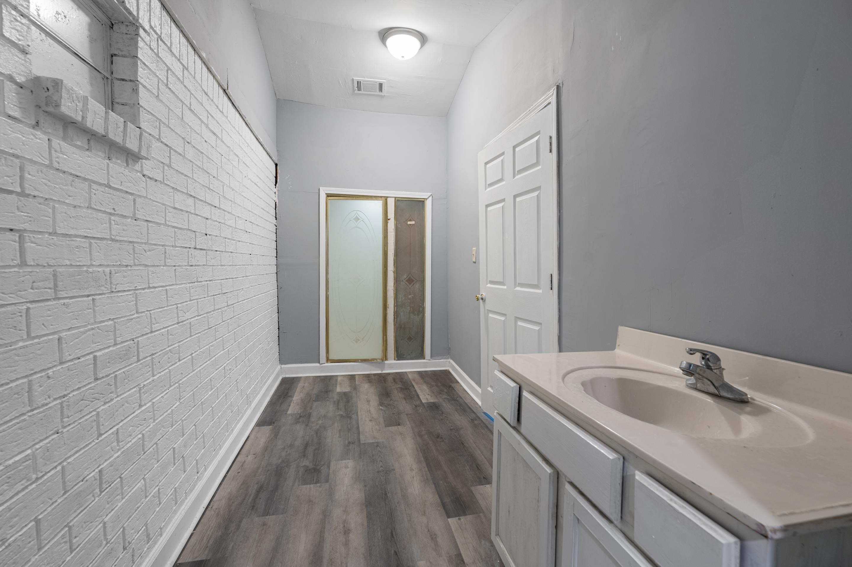 726 Harahan Road Memphis, TN 38109 - Photo 17 of 24 Bathroom featuring brick wall, wood finished floors, and vanity