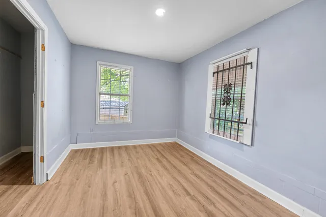 a view of an empty room with wooden floor and a window