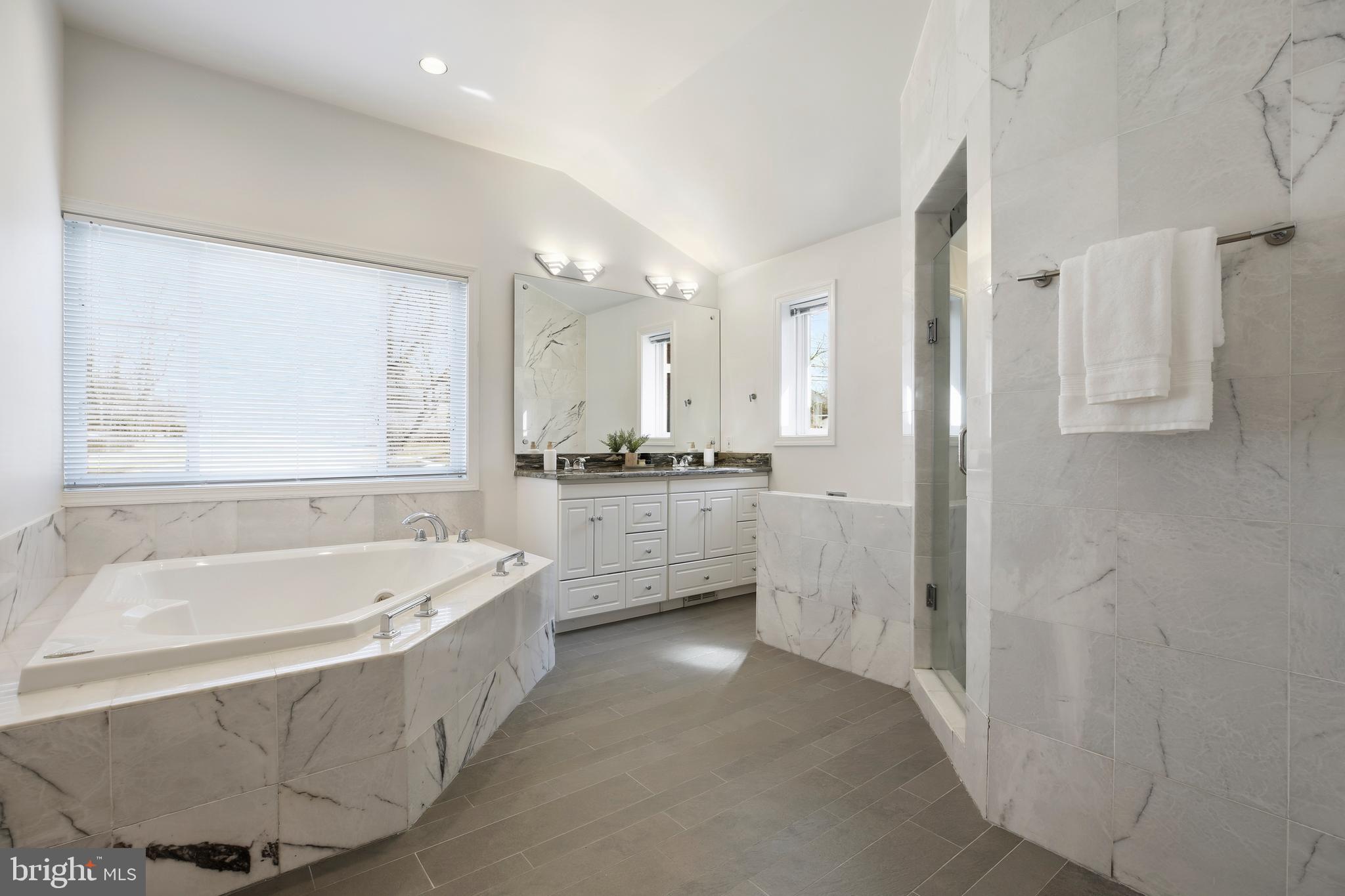 9914 Fernwood Road Bethesda, MD 20817 - Photo 28 of 61 a bathroom with a tub a double vanity sink a window and a shower