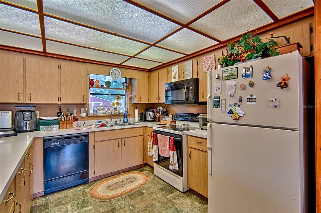 6537 Triest Avenue Keystone Heights, FL 32656 - Photo 12 of 36 a kitchen with stainless steel appliances granite countertop a refrigerator a stove a sink dishwasher and white cabinets with wooden floor