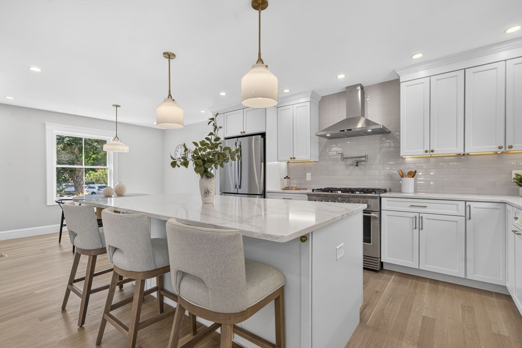 20 Saltonstall Road Medford, MA 02155 - Photo 9 of 41 a kitchen with stainless steel appliances granite countertop a sink a stove a refrigerator and white cabinets with wooden floor