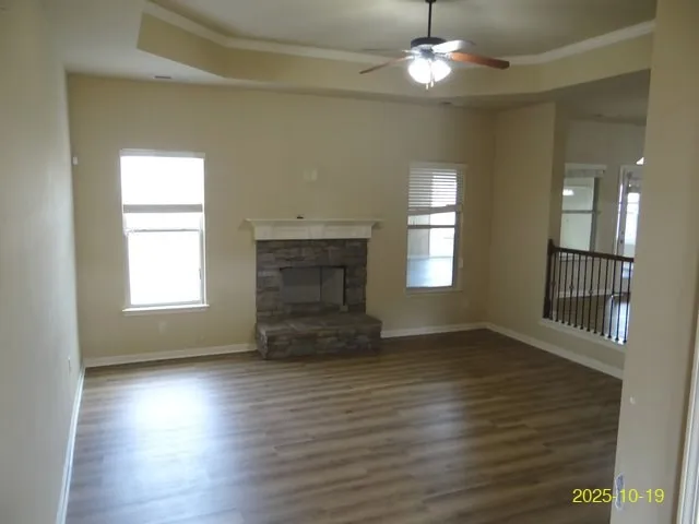 an empty room with wooden floor chandelier and windows