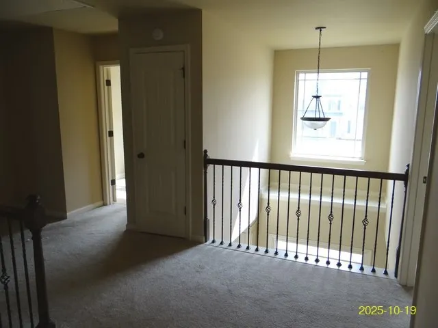 a view of a hallway to window and chandelier