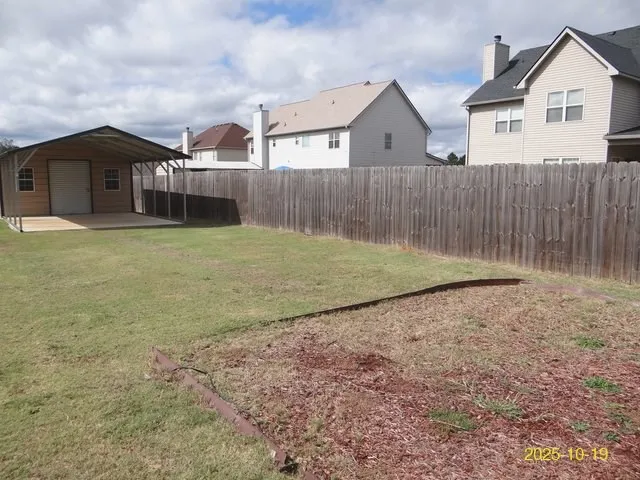 a backyard of a house with a large tree and wooden fence