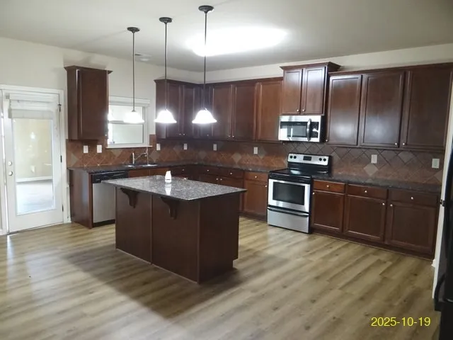 a kitchen with stainless steel appliances granite countertop a sink counter space cabinets and wooden floor