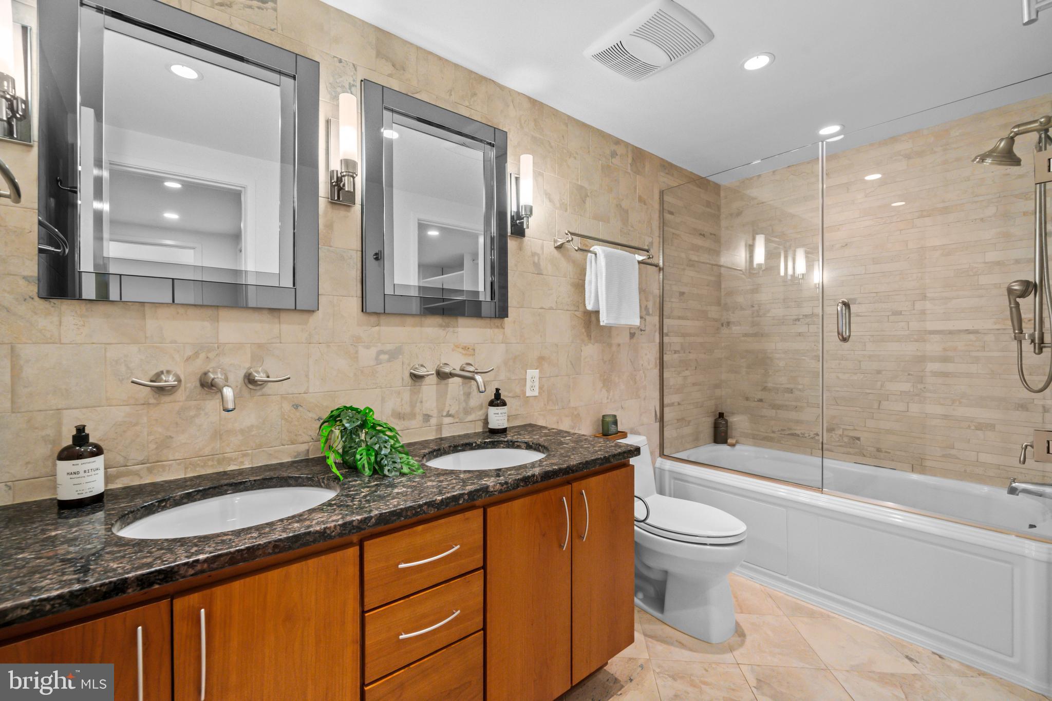 3225 Grace Street Northwest, Unit 219 Washington, DC 20007 - Photo 28 of 44 a bathroom with a granite countertop sink a toilet a mirror and bathtub