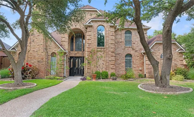 a front view of a house with garden and trees