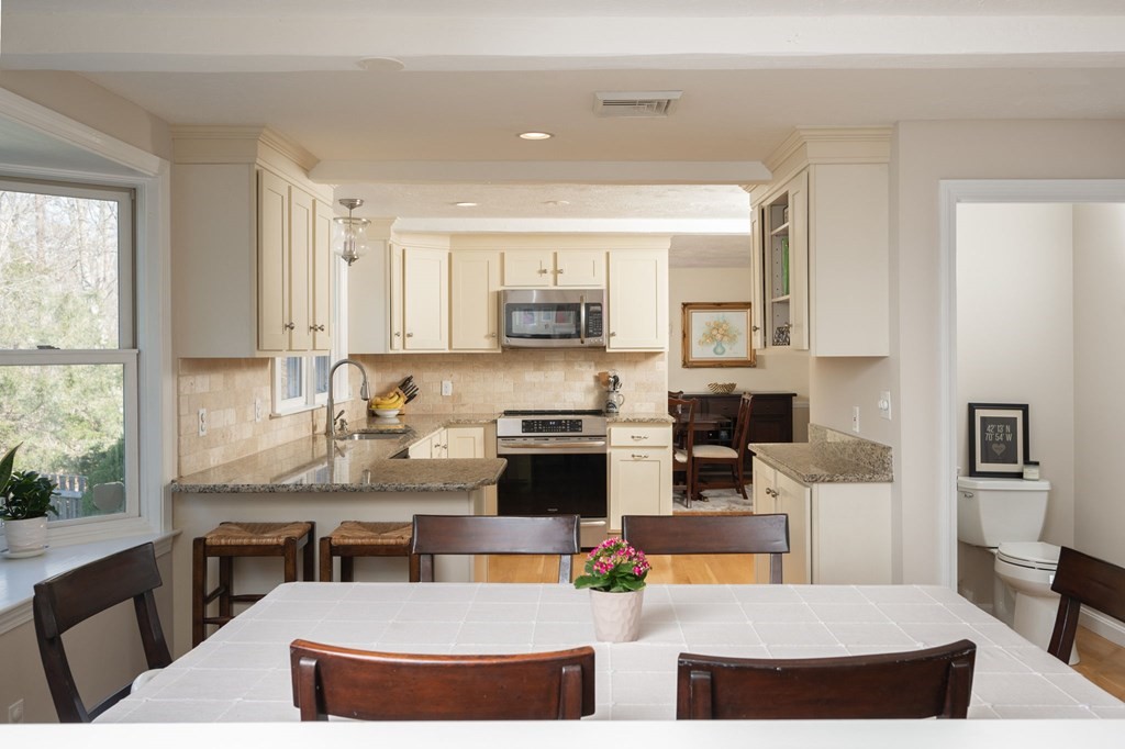 5 Chatham Circle Hingham, MA 02043 - Photo 7 of 30 a kitchen with stainless steel appliances granite countertop a stove a sink a microwave a dining table and chairs