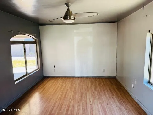 a view of empty room with wooden floor and fan