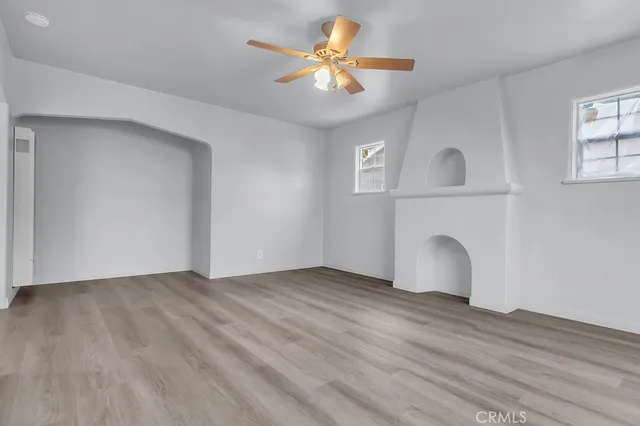 a view of an empty room with a window and wooden floor