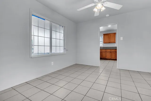 an empty room with chandelier fan and windows
