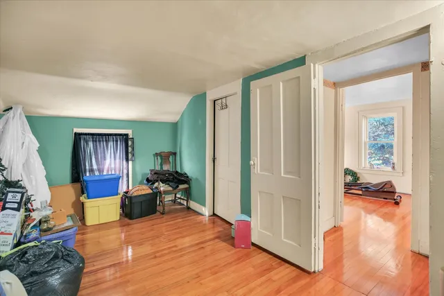 a view of an empty room with window and wooden floor