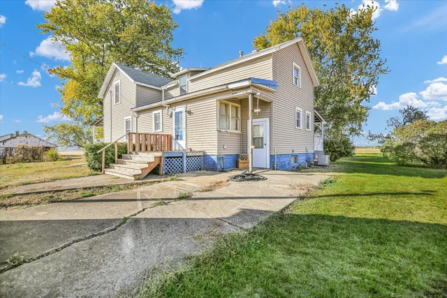 a view of a white house with a big yard and large tree