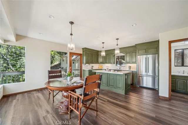 a kitchen with stainless steel appliances kitchen island granite countertop a table chairs and a wooden floor