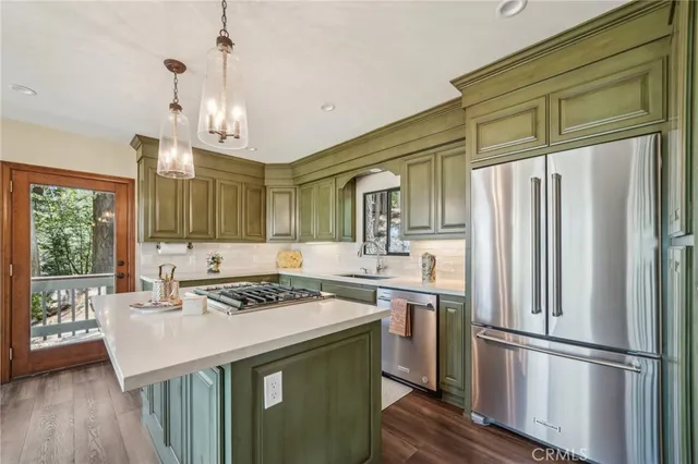 a kitchen with stainless steel appliances granite countertop a refrigerator a stove and a wooden floors