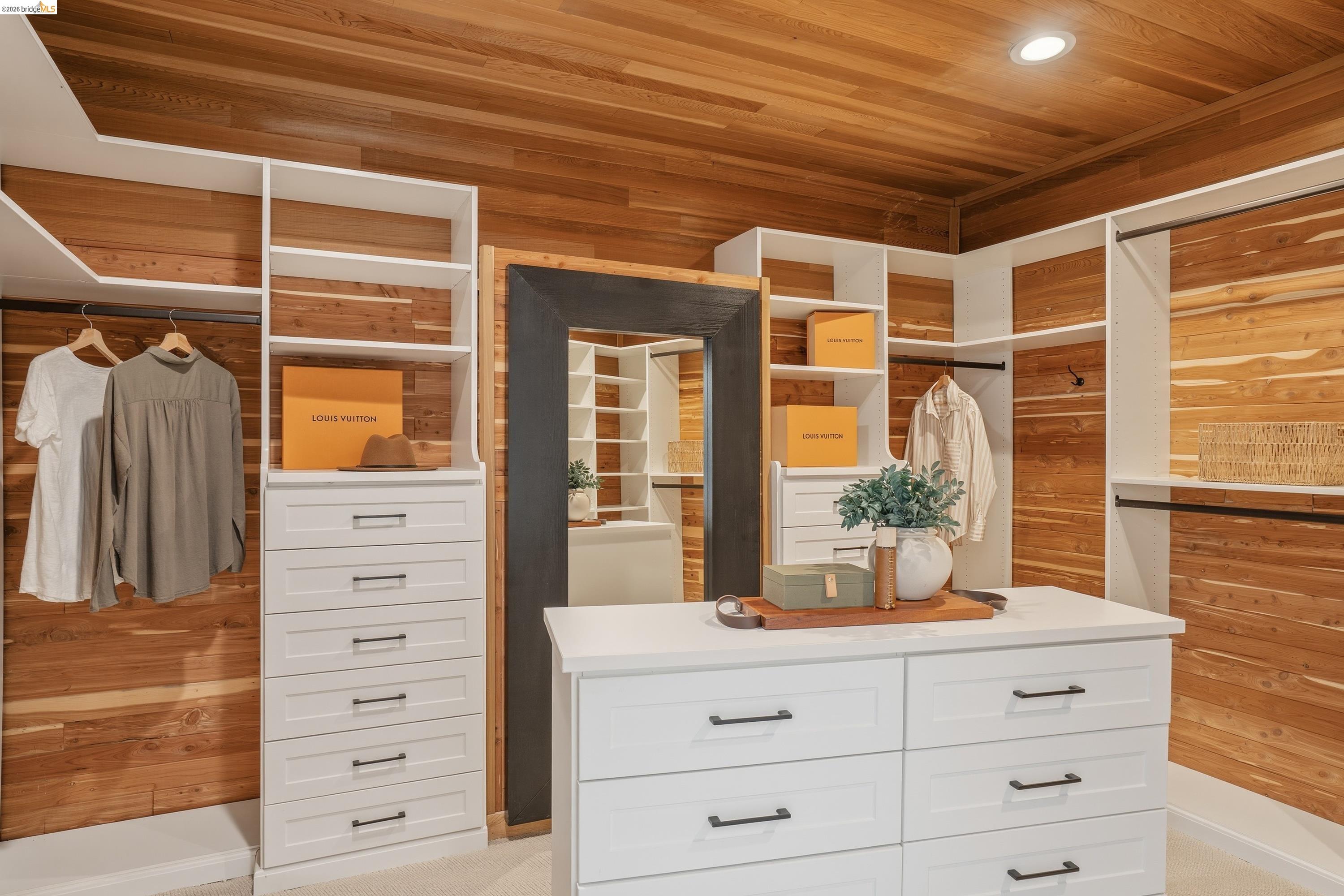 4120 Happy Valley Road Lafayette, CA 94549 - Photo 18 of 33 Custom closet featuring wood-finish walls and ceiling, white built-in cabinetry with dark hardware, a central island with countertop, and recessed ceiling lighting
