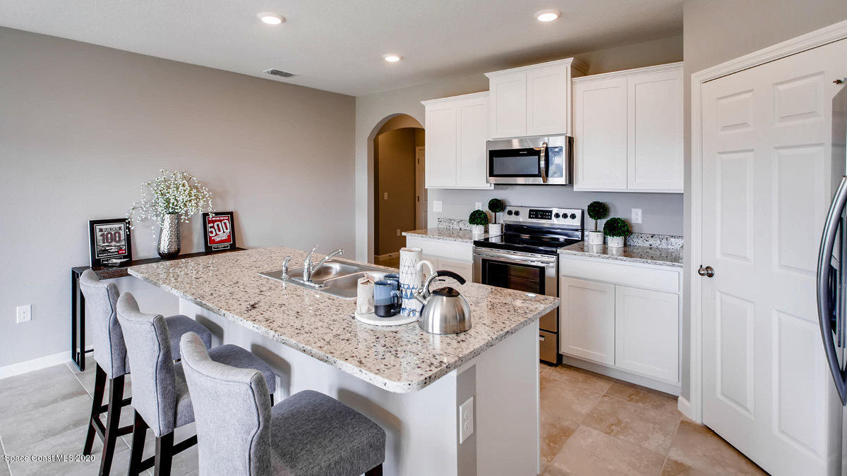 578 Old Country Rd S East Palm Bay, FL 32909 - Photo 2 of 26 a kitchen with stainless steel appliances granite countertop a stove a sink a microwave a refrigerator and cabinets