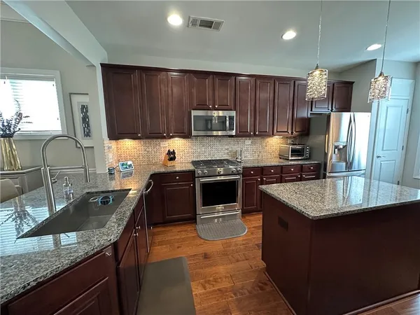 a kitchen with stainless steel appliances granite countertop a stove refrigerator sink and microwave
