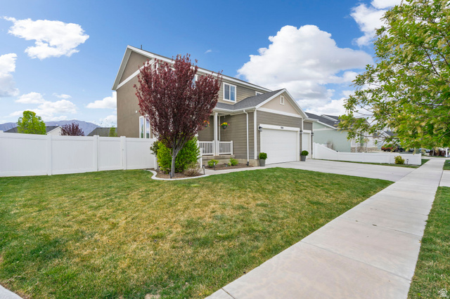 7685 Timber Country Road Eagle Mountain, UT 84005 - Photo 2 of 39 Two-story residence featuring a two-car garage, white vinyl fencing, and a front porch