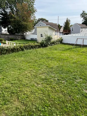 a view of a white house with a big yard and large trees