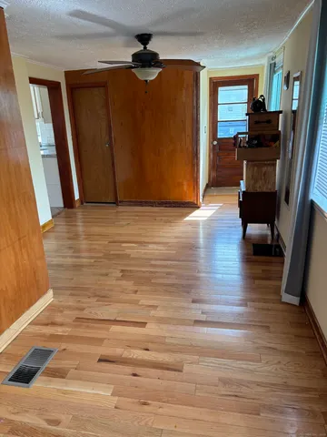 a view of empty room with wooden floor and fan