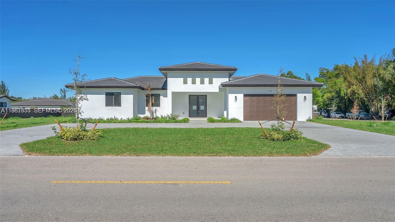 15455 Southwest 232nd Street, Unit A Miami, FL 33170 - Photo 3 of 12 a front view of a house with a yard and garage