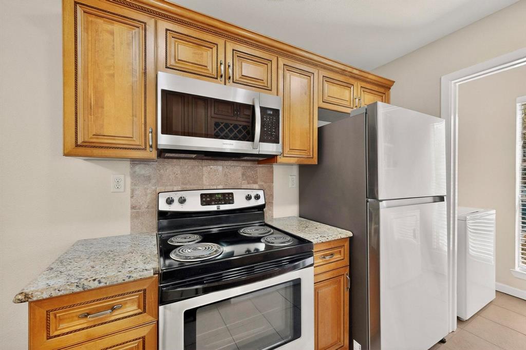 5981 Arapaho Road, Unit 901 Dallas, TX 75248 - Photo 21 of 38 a kitchen with stainless steel appliances granite countertop a stove microwave and refrigerator