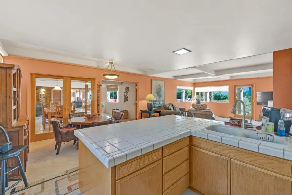 a kitchen with a stove a sink and living room view