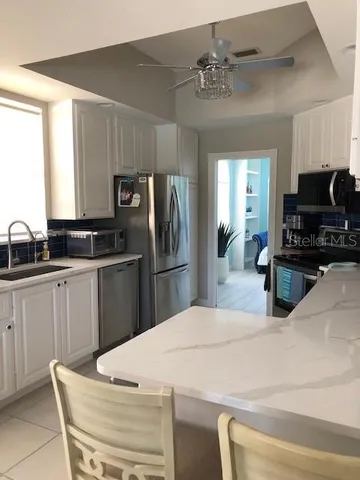 a kitchen with stainless steel appliances a stove a microwave a sink and white cabinets