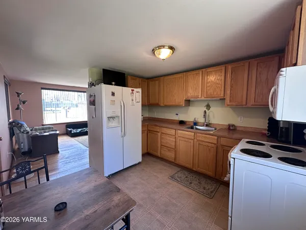 a kitchen with a refrigerator a stove a sink a dining table and chairs