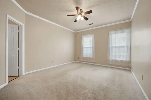 an empty room with windows and fan