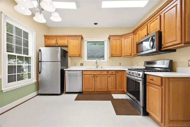 a kitchen with stainless steel appliances granite countertop a refrigerator a sink dishwasher a dining table and chairs with wooden floor