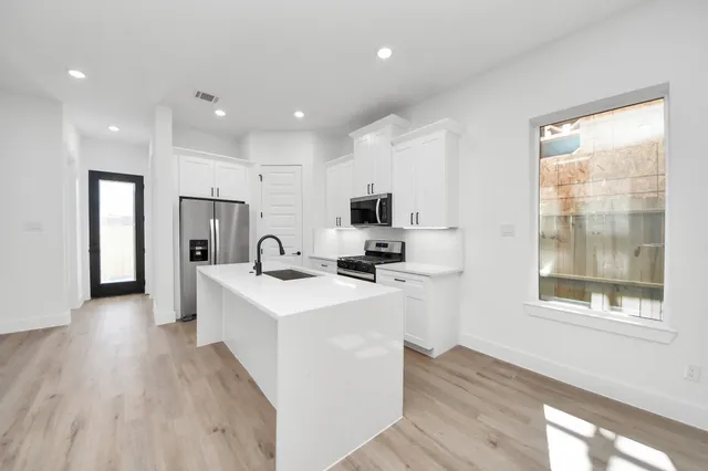 a kitchen with stainless steel appliances a refrigerator a sink dishwasher and a stove with wooden floor