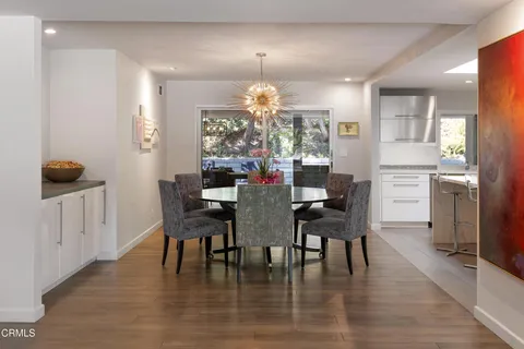 a kitchen with stainless steel appliances kitchen island granite countertop a table chairs sink and cabinets