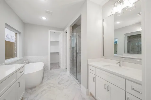 a spacious bathroom with a double vanity sink toilet mirror and bathtub