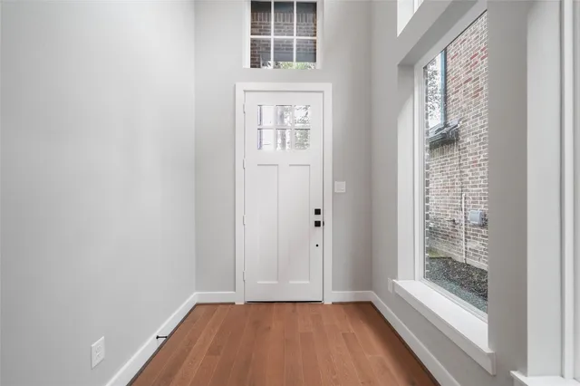 a view of an empty room with a window and wooden floor