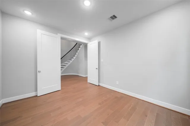 a view of an empty room with wooden floor and closet