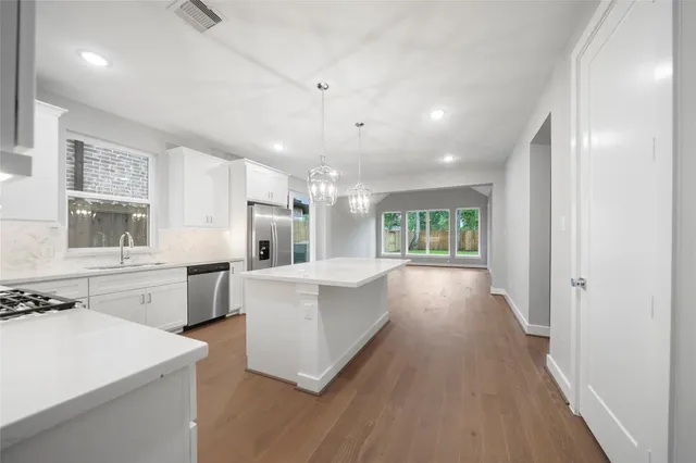 a large white kitchen with window and stainless steel appliances