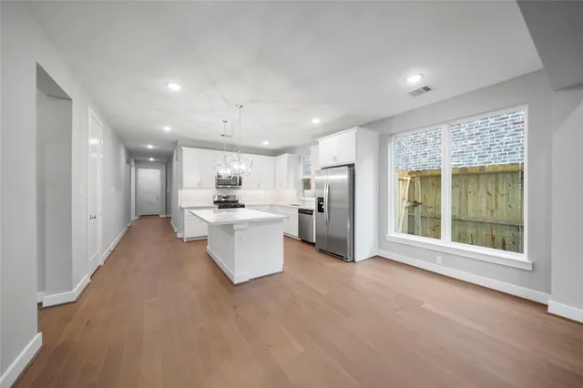 a view of a kitchen with a sink and dishwasher a refrigerator with white cabinets