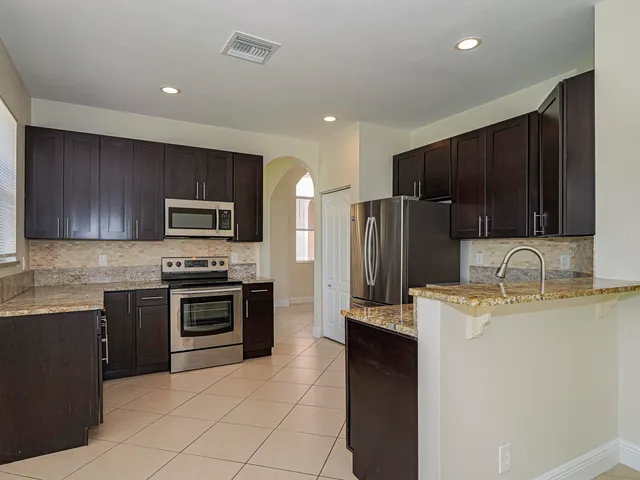 a kitchen with stainless steel appliances granite countertop a stove top oven a sink dishwasher a refrigerator and a microwave