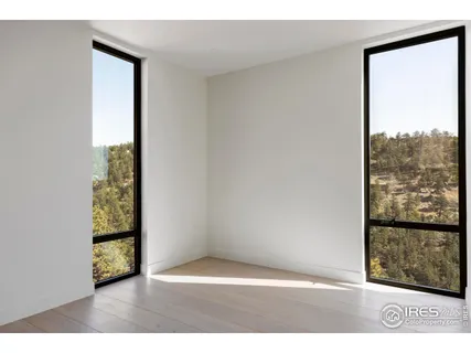 a view of an empty room with wooden floor and windows