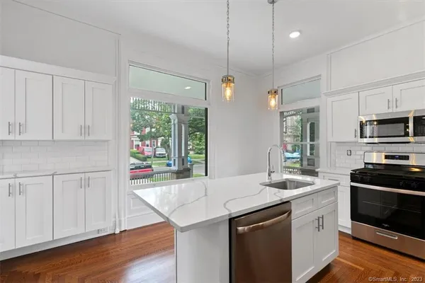 a kitchen with stainless steel appliances granite countertop a sink a stove and a wooden floors