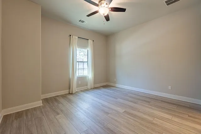 an empty room with a hardwood and ceiling fan