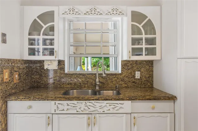a kitchen with stainless steel appliances granite countertop white cabinets and a window