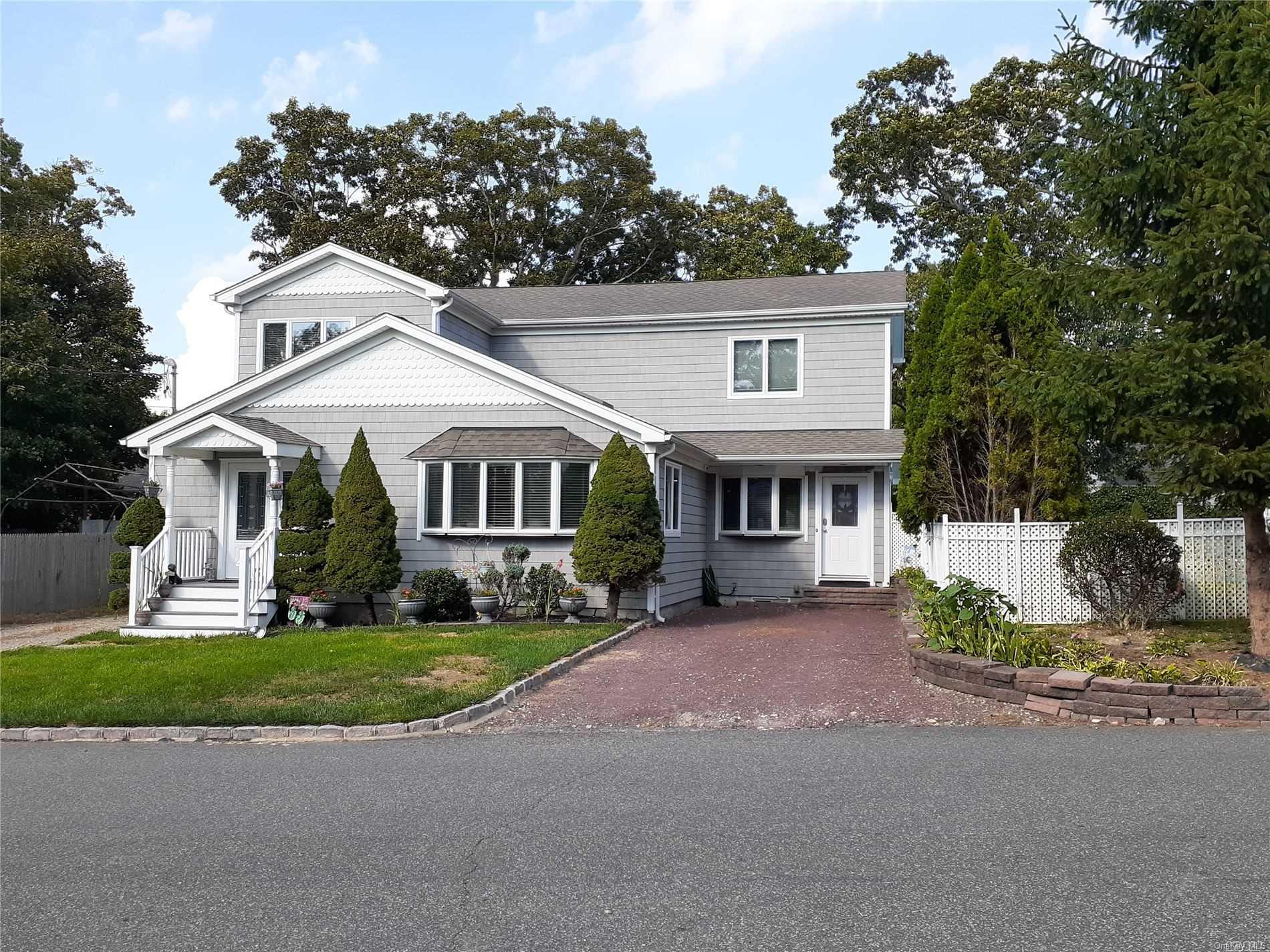 a front view of a house with a garden and trees