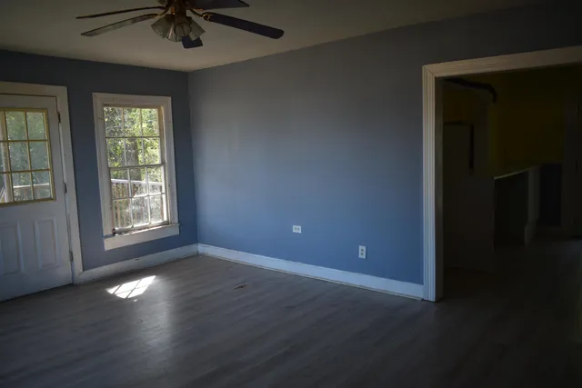 an empty room with wooden floor and windows