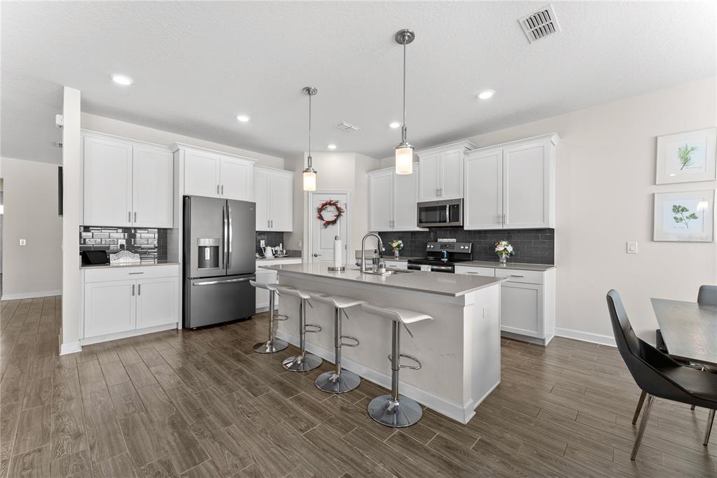 2926 Wordsmith Road Kissimmee, FL 34746 - Photo 20 of 42 a kitchen with stainless steel appliances kitchen island granite countertop a refrigerator a stove a sink and white cabinets with wooden floor