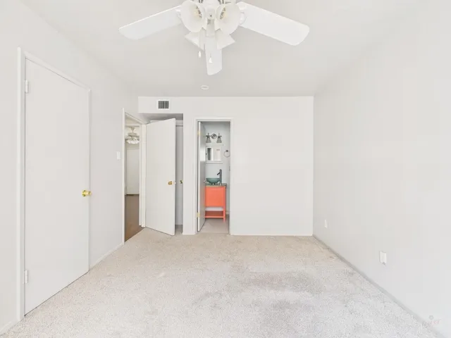 an empty room with a chandelier fan and closet