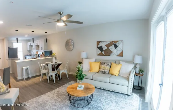 a living room with furniture kitchen view and a large window